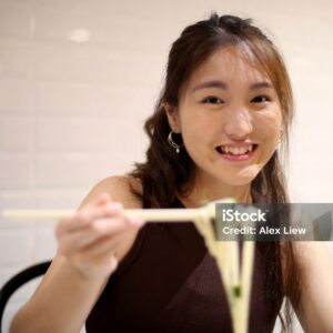 An Asian young woman is enjoying Japanese udon seaweed noodle in restaurant